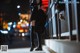 A woman in a black dress is walking down the street at night.