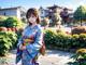 A woman in a kimono standing in front of a flower garden.