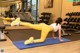 A woman doing a plank on a blue mat in a gym.