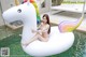 A woman in a white bikini sitting on an inflatable unicorn float.