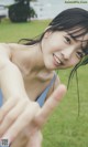 A woman in a blue tank top is making a peace sign.