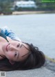 A woman laying on the edge of a concrete wall by the water.