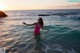 A woman in a pink bathing suit standing in the ocean.