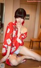 A woman in a red kimono sitting on the floor.