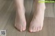 A close up of a person's bare feet on a wooden floor.